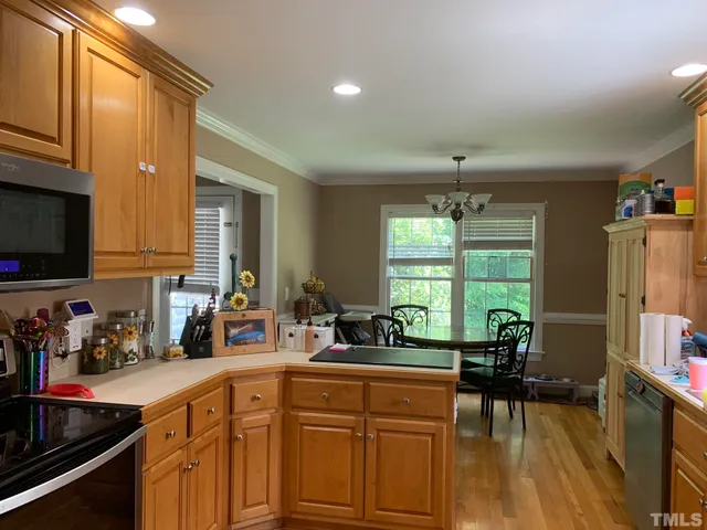 a kitchen with stainless steel appliances granite countertop a sink dishwasher stove and cabinets with wooden floor