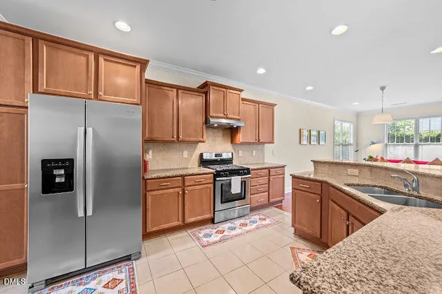 a kitchen with stainless steel appliances granite countertop a refrigerator stove top oven and sink