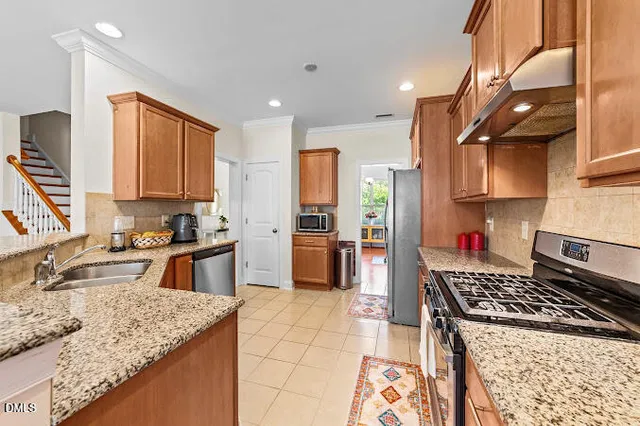 a kitchen with stainless steel appliances granite countertop a stove a sink and a refrigerator