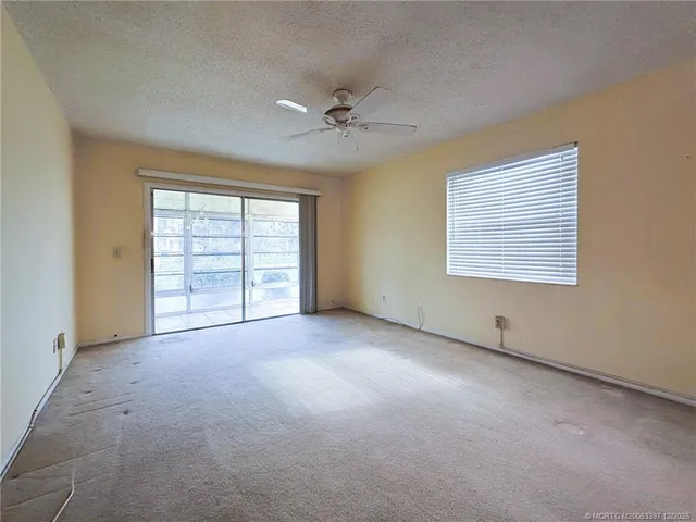 an empty room with windows and ceiling fan
