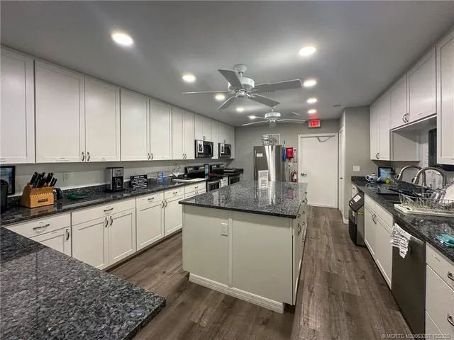 a kitchen with stainless steel appliances granite countertop a sink a stove and cabinets
