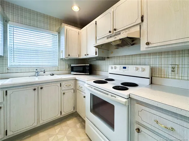 a kitchen with granite countertop white cabinets and white appliances