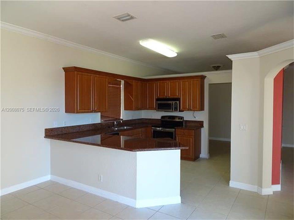 12830 Southwest 51st Street Miramar, FL 33027 - Photo 2 of 7 a kitchen with stainless steel appliances granite countertop a sink and a refrigerator