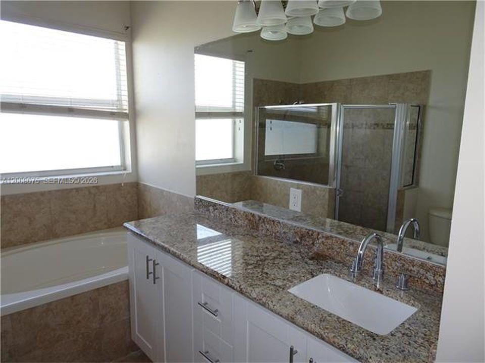 12830 Southwest 51st Street Miramar, FL 33027 - Photo 4 of 7 a bathroom with a granite countertop sink mirror and a bathtub