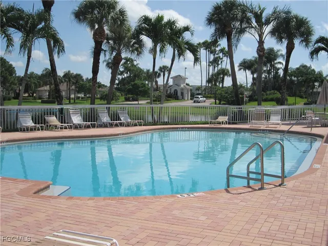 a view of swimming pool with a lawn chairs and palm trees