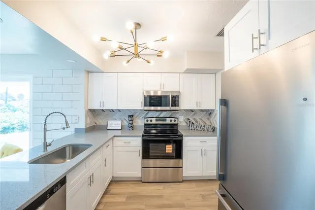 a kitchen with stainless steel appliances a stove a microwave and white cabinets