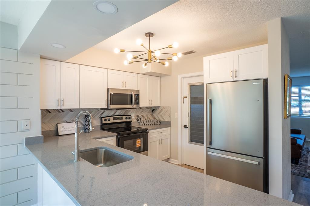 24 Berkley Road Ormond Beach, FL 32176 - Photo 10 of 44 a kitchen with stainless steel appliances granite countertop a refrigerator a stove a sink and a stove with wooden floor