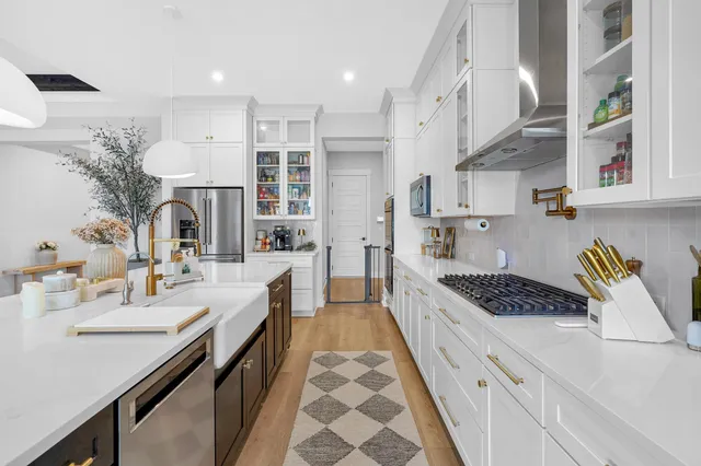 a large white kitchen with a sink and dishwasher a stove with wooden floor