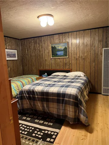 a bedroom with a bed and a dresser with wooden floor