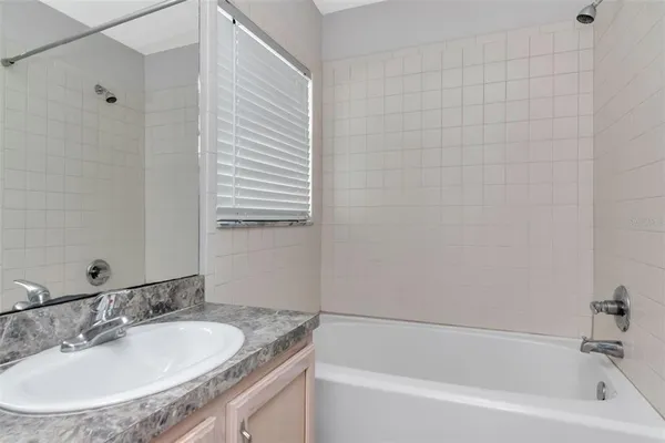 a bathroom with a granite countertop sink and a bathtub