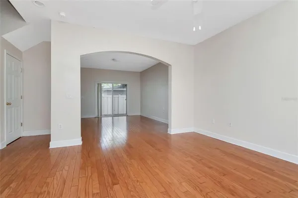 a view of empty room with wooden floor and fan