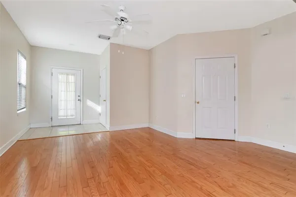 a view of an empty room with wooden floor and a window