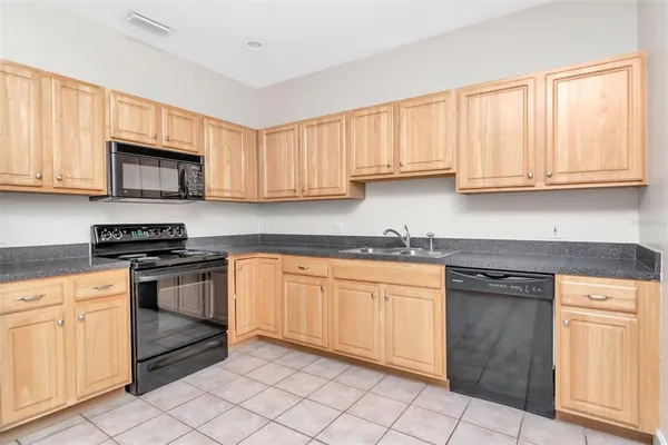 a kitchen with granite countertop white cabinets sink and stainless steel appliances