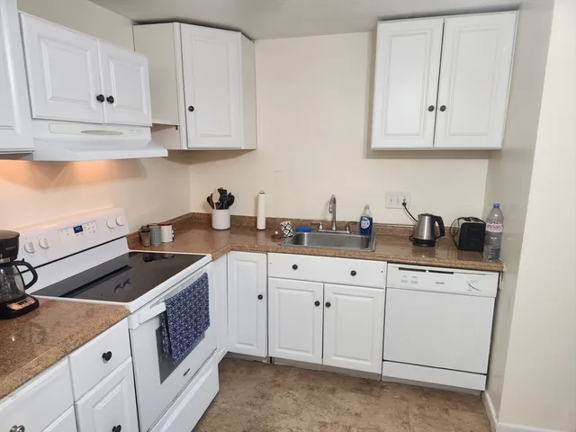 a kitchen with white cabinets and sink