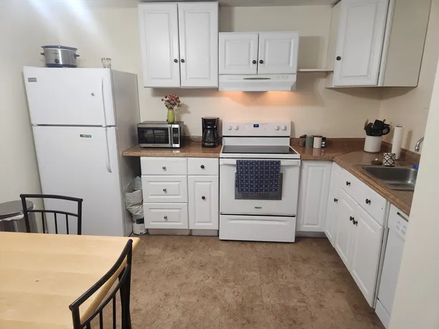 a kitchen with white cabinets and white appliances