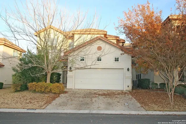 a view of a white house with a large tree