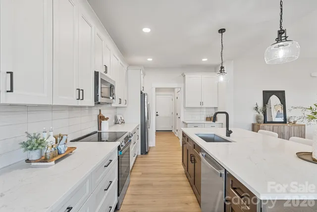 a kitchen with stainless steel appliances granite countertop a sink a stove and a wooden floors
