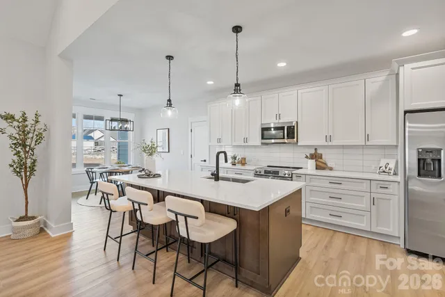 a large kitchen with kitchen island a dining table chairs and white cabinets