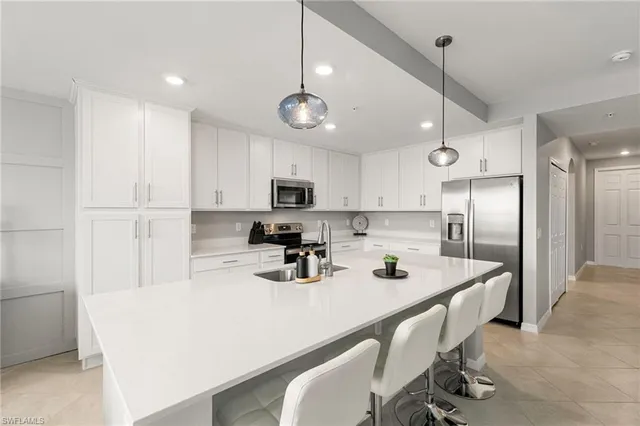 a kitchen with stainless steel appliances a sink a stove a refrigerator cabinets and chairs