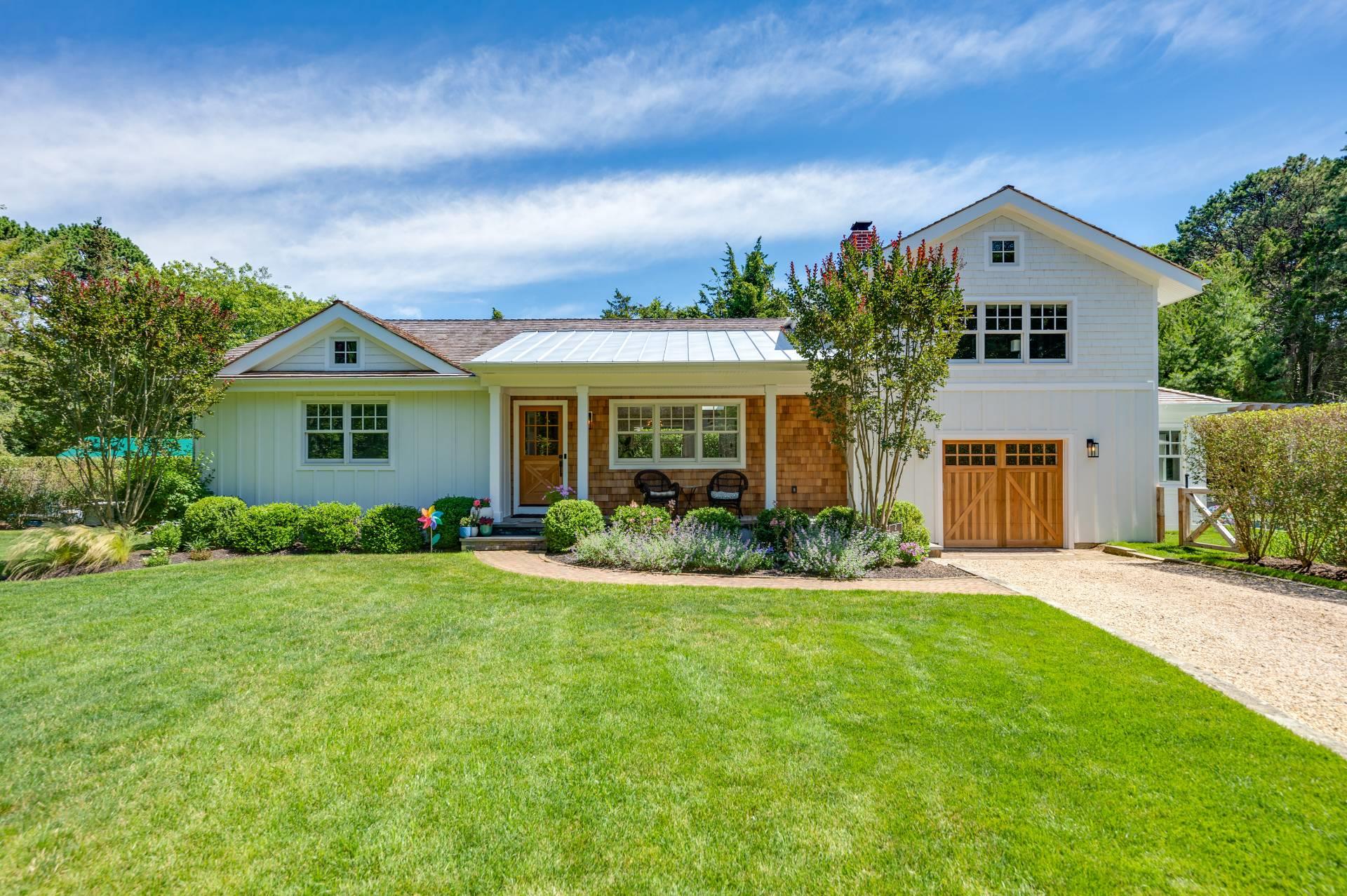 View of front of property featuring a chimney, driveway, a front yard, a garage, and board and batten siding