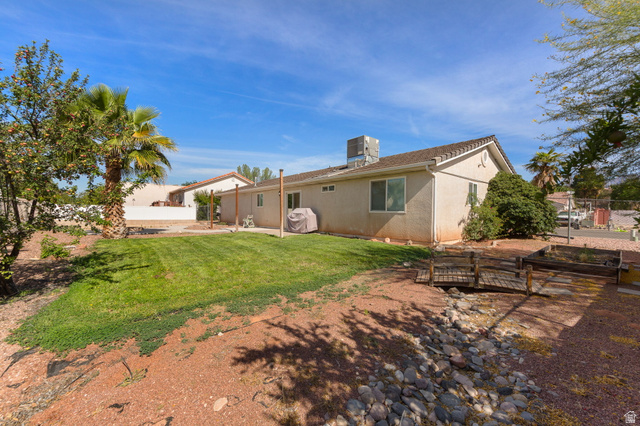 664 East Springhill Drive Washington, UT 84780 - Photo 19 of 21 Expansive backyard featuring a manicured lawn, a decorative wooden bridge over a dry creek bed, and mature trees
