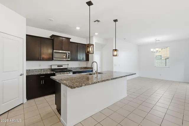 a kitchen with stainless steel appliances granite countertop a sink a stove a microwave and a refrigerator