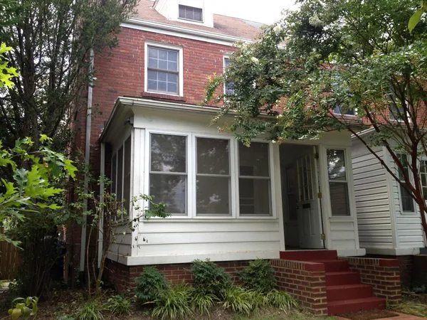 a view of brick house with a large windows and flower plants