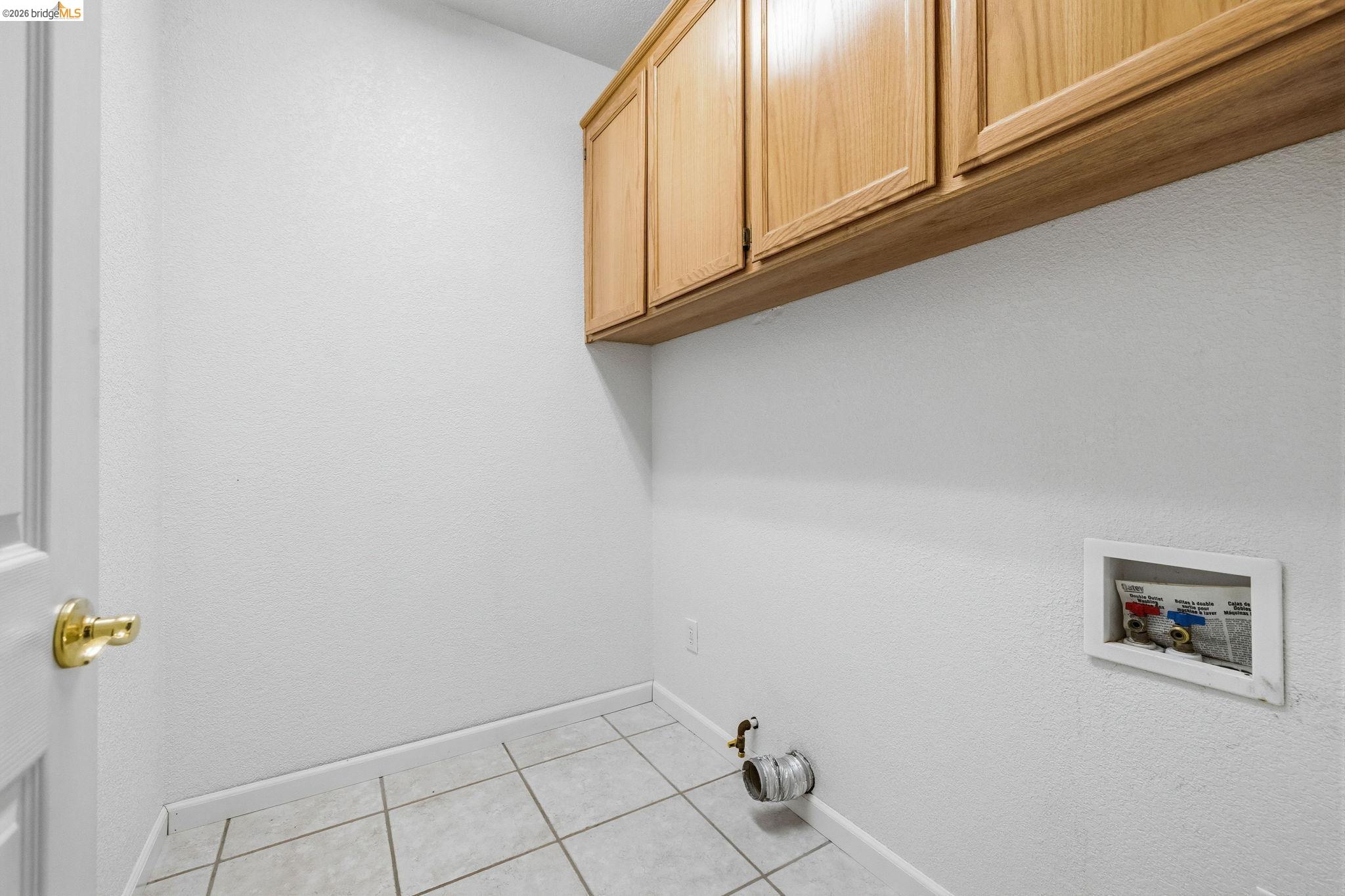 18450 Lambert Lake Road Sonora, CA 95370 - Photo 56 of 87 Dedicated utility space featuring light wood-finish cabinetry, tile flooring, and a washing machine hookup