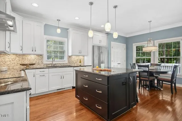 a kitchen with granite countertop a sink a center island and stainless steel appliances