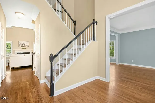 a view of a hallway with wooden floor staircase and a living room