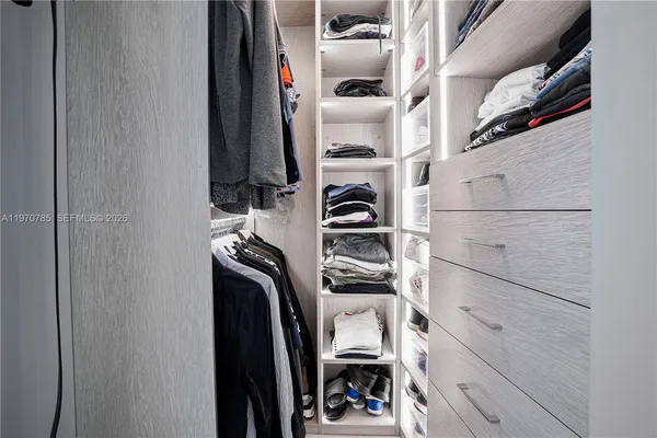 a view of walk in closet with clothes and shoes