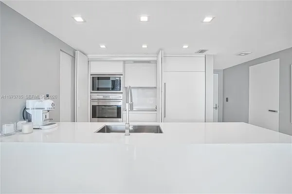 a large white bedroom with kitchen area and a refrigerator