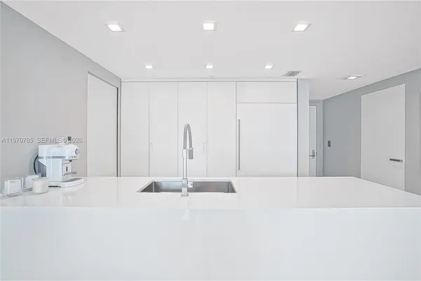 a large white kitchen with sink and a refrigerator