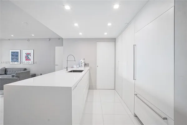 a large white kitchen with sink and refrigerator