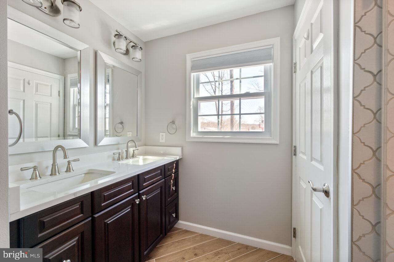 2405 Cedar Lane Vienna, VA 22180 - Photo 31 of 56 a en suite bathroom with a double vanity sink a mirror and a window