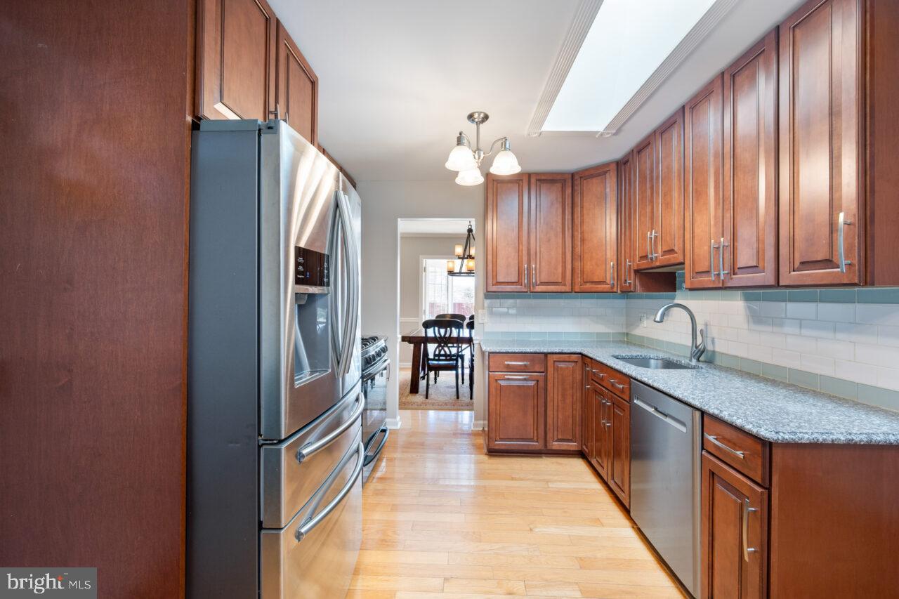 2405 Cedar Lane Vienna, VA 22180 - Photo 34 of 56 a kitchen with granite countertop a sink stainless steel appliances wooden floor and cabinets