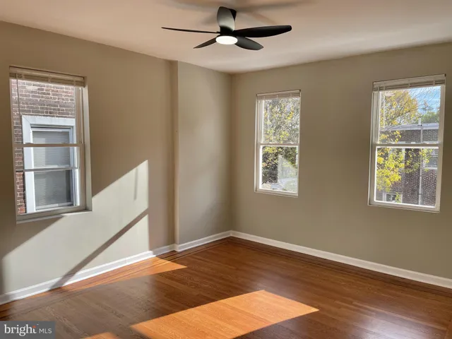 a view of an empty room with a window and wooden floor