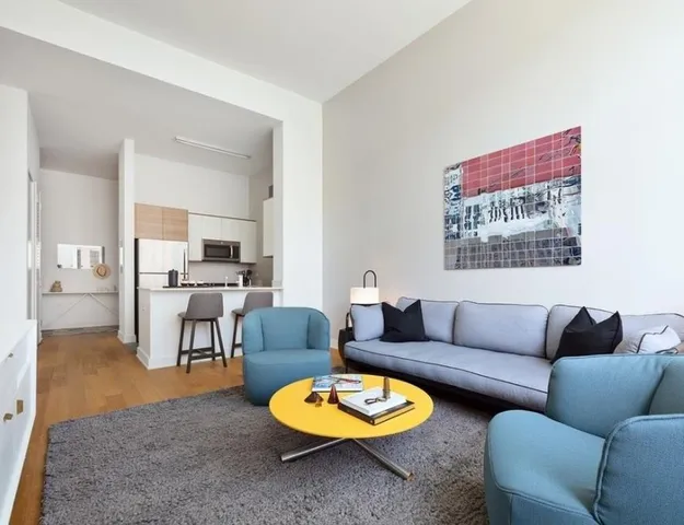 a living room with furniture a rug kitchen view and a window