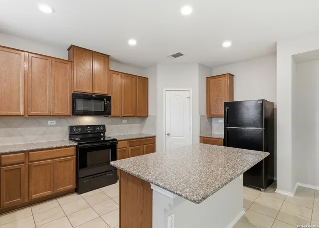 a kitchen with stainless steel appliances granite countertop a sink dishwasher stove and refrigerator with wooden floor