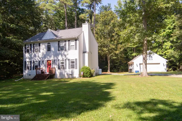 a view of a house with a big yard and large trees