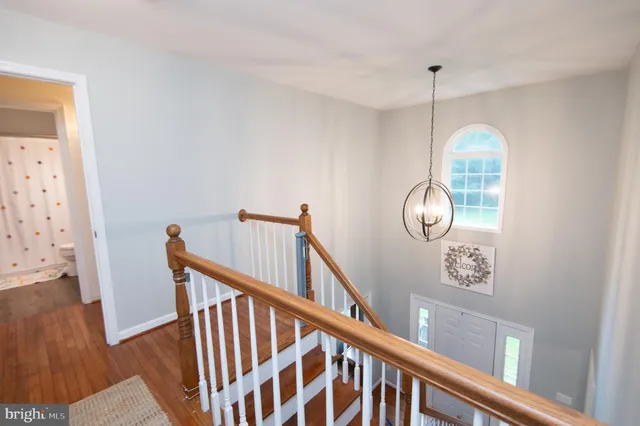 a view of a hallway to room with wooden floor and windows