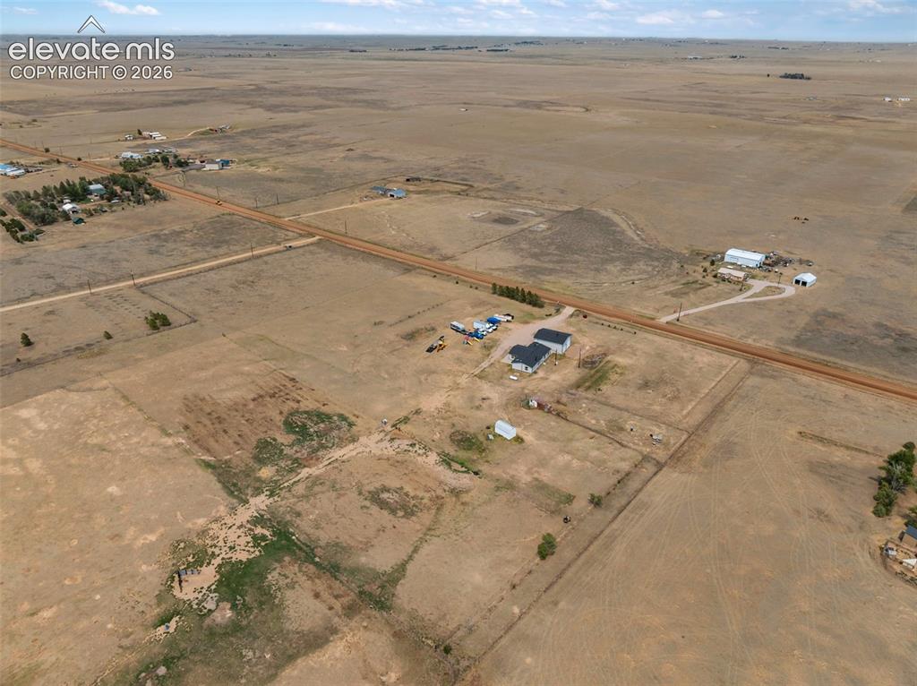 1350 South Calhan Highway Yoder, CO 80864 - Photo 45 of 45 Expansive rural landscape featuring a single-story residence with a dark roof and a detached outbuilding