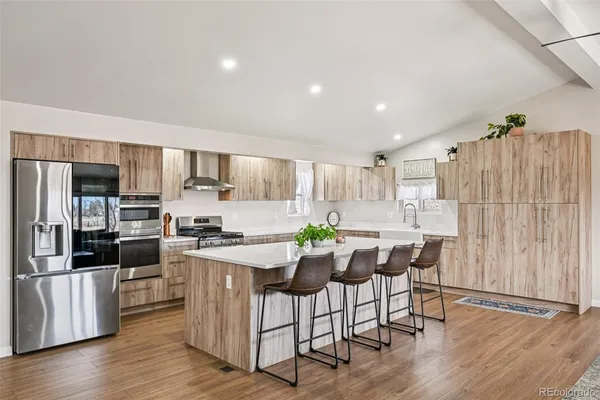 a kitchen with stainless steel appliances a dining table chairs stove refrigerator and microwave