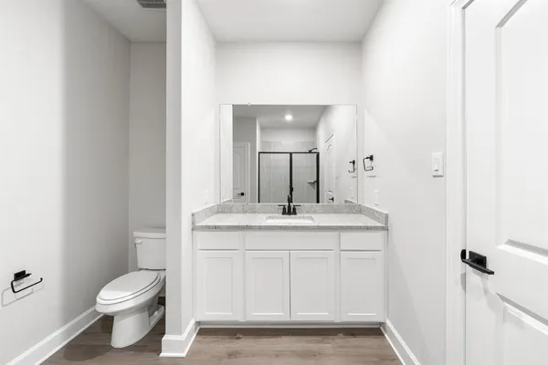 a bathroom with a granite countertop toilet a sink and a mirror