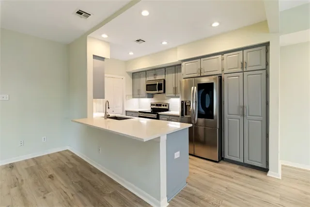 a kitchen with stainless steel appliances granite countertop a refrigerator a sink a stove a microwave and wooden floor