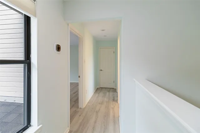 a view of a hallway with wooden floor and a bathroom