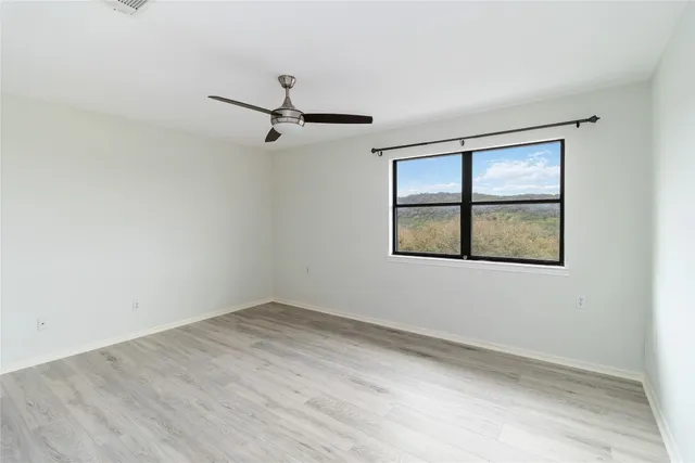 an empty room with windows and ceiling fan