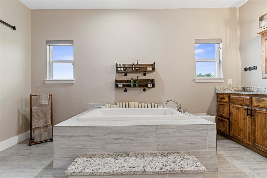 139 Kriston Lane Springtown, TX 76082 - Photo 27 of 39 Spacious bathroom featuring a built-in soaking tub with light-toned tile surround and a granite-topped step