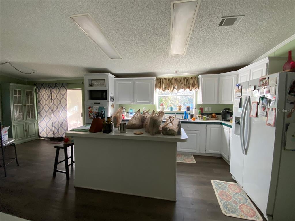 31244 Tyndall Road Zephyrhills, FL 33545 - Photo 4 of 24 a kitchen with stainless steel appliances a refrigerator a sink dishwasher a stove and a dining table with wooden floor