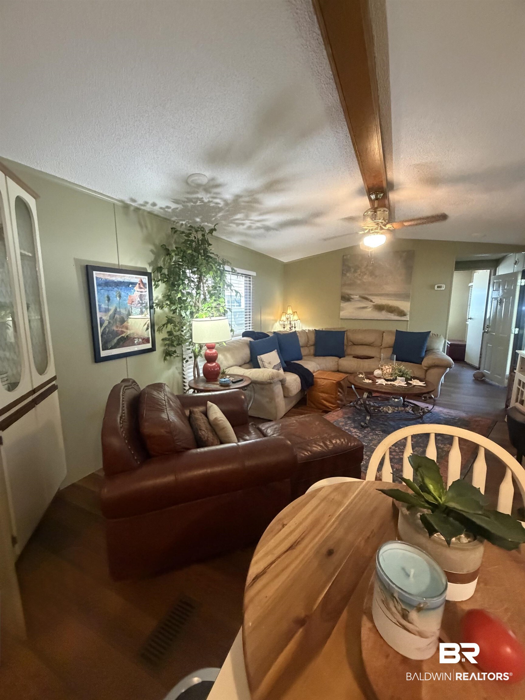 1620 Del Rey Drive Lillian, AL 36549 - Photo 11 of 45 Living area featuring wood-finish flooring, a vaulted ceiling with an exposed wood beam, a ceiling fan, and light green walls